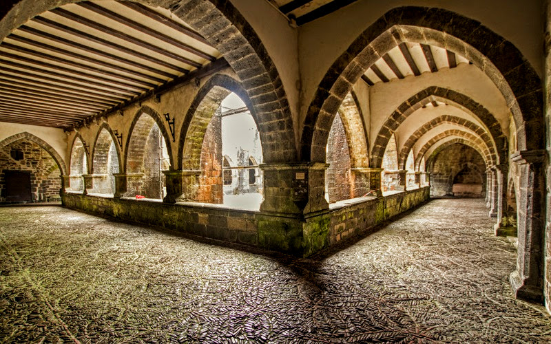 claustro com quatro arcos ogivais em cada um dos quatro lados e chão decorado em pedras