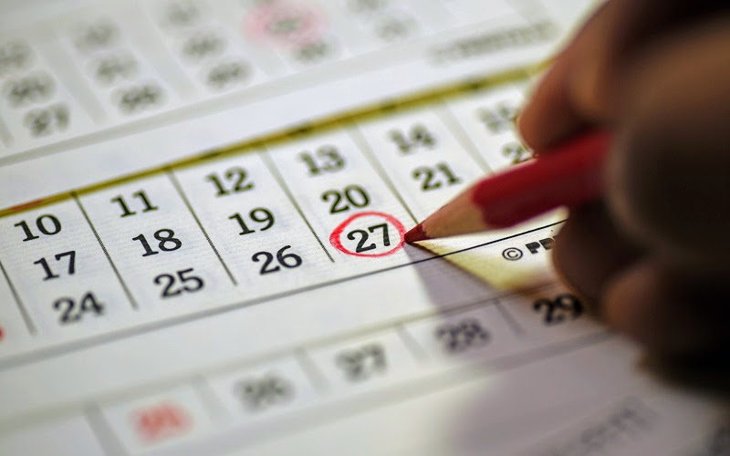 pessoa circulando com lápis vermelho uma data em um calendário