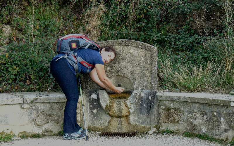 peregrina pegando água em uma fonte