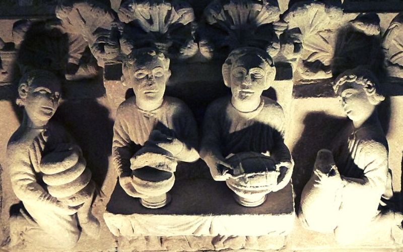 escultu em pedra de um banquete medieval com quatro pessoas