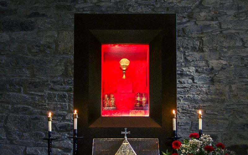 altar de igreja com um relicário, um calice, ema patena e velas acessaa
