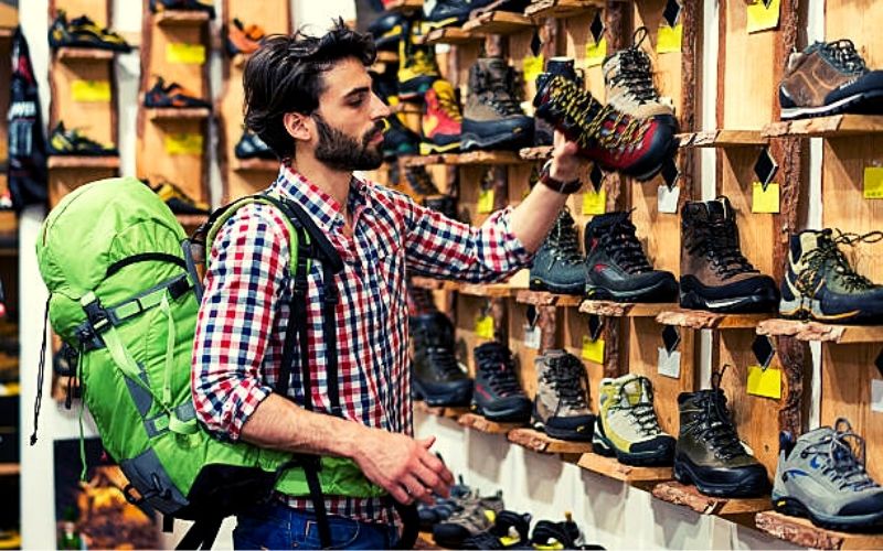 homem escolhendo calçado em loja de esportes de aventura
