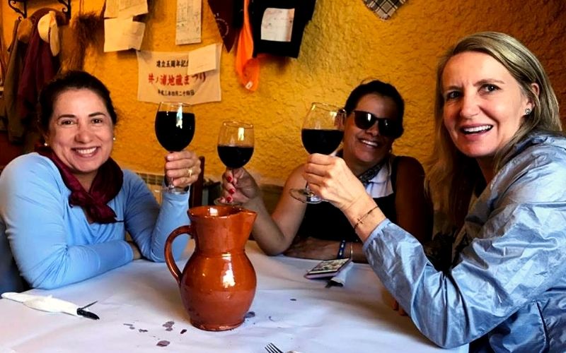 três mulheres brindando com vinho tinto