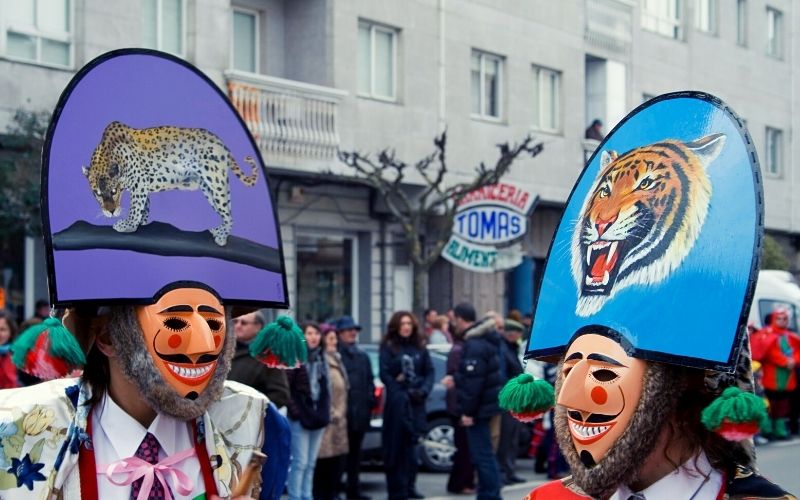 duas pessoas com máscaras de homens sorrindo, com barba e um chapéu no estilo de Napoleão 