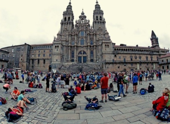 inumeras pessoas em uma praza admirando a fachada de uma catedral