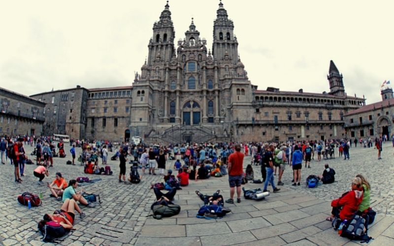 inumeras pessoas em uma praza admirando a fachada de uma catedral