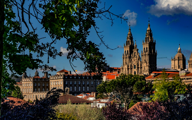 imagem da catedral de Santiago de Compostela rodeada de jardins em dia de céu azul