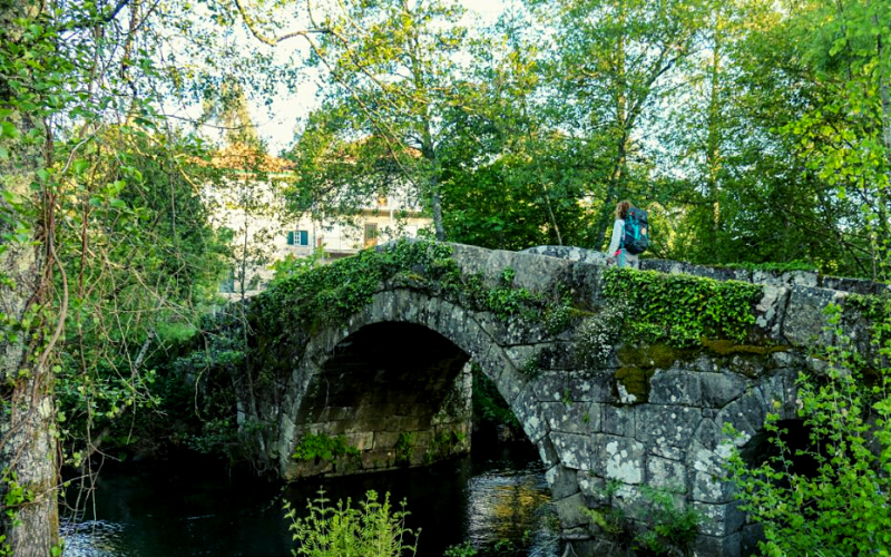 pessoa atravessando uma ponte medieval de pedra
