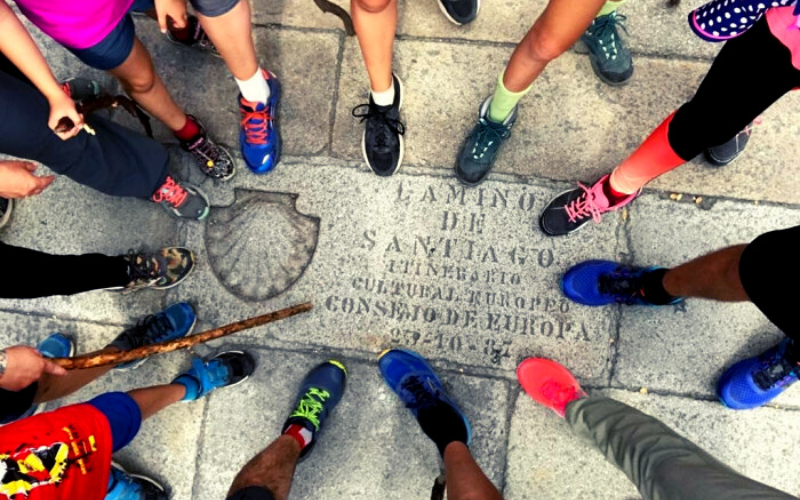 pés de peregrinos circulando o marco zero do caminho de santiago na plaza del obradoiro