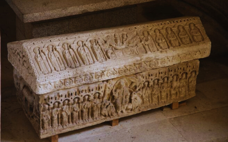 túmulo de pedra todo esculpido com imagens de figuras, cenas e relevos 