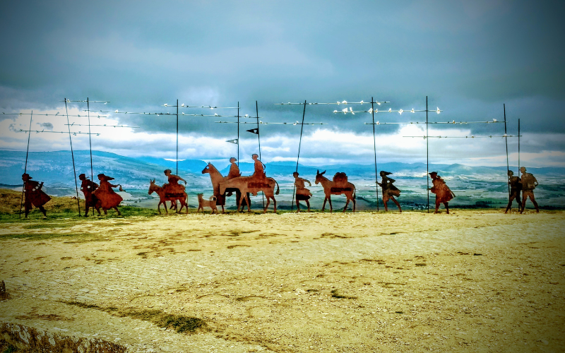 grupo de esculturas de ferro sobre uma colina, representando uma comitiva de peregrinos sobre cavalos e carregando mastros