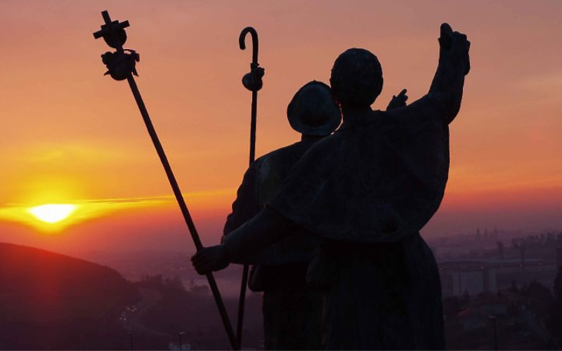 silueta da umagem de dois peregrinos se aproximando da catedral de santiago de compostela ao por do sol
