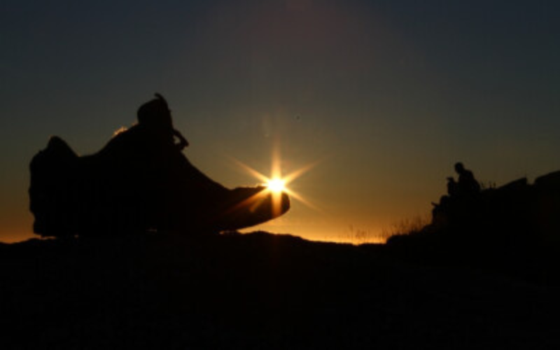 silueta de uma bota com o sol no horizonte
