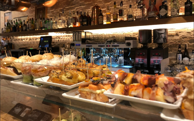 balcão de um bar coberto de badejas com diversos tipos de petiscos