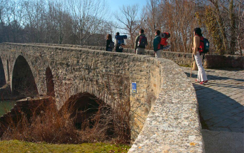 peregrinos atravessando uma ponte medieval